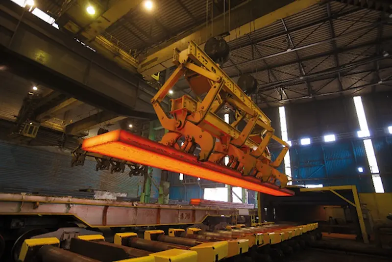 Manipulación de acero caliente con sistema automatizado en entorno industrial